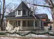 Late-19th century cottage in a former Toronto municipality with a conical turret, porch, and festive garlands.