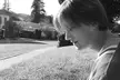 Black and white profile of a blonde girl in a ribbed top looking down on a residential street.