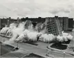 The demolition of the Pruitt–Igoe housing project in St. Louis, Missouri, showing a building collapsing into a dust cloud.