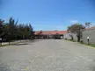 Abandoned SESC Hotel in São João da Barra, Brazil, with a cobblestone road and red roof building.