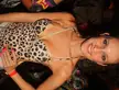 A blonde woman in a leopard print halter top and denim shorts smiling in a crowd