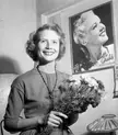 Svedlund, a smiling blonde woman with curly hair, holding a bouquet of flowers in a black and white vintage photo