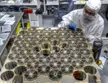 A person in a white cleanroom suit and blue gloves working on the Neutron Star Interior Composition Explorer array.
