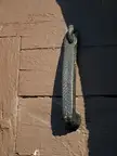 Close-up of a dark metal handle on a brown painted wooden surface in Detalles de Gumiel 2