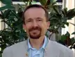 Philippe Sautet, Member of the French Academy of sciences, wearing a light blazer and striped shirt against green foliage