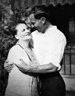 Emilie and Emory embracing in a black and white vintage photo, wearing a white shirt and patterned top.