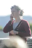 A beautiful woman with brown hair in a bun wearing a maroon zip-up hoodie and sunglasses on her head.