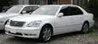 Two white Lexus LS sedans parked on gravel in front of a building.