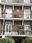 James Hanley's London home, a brick building with balconies, white window frames, and black wrought iron railings.