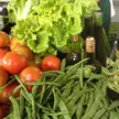Cursed food close-up of green lettuce, red tomatoes, green beans, and small glass bottles in a market setting
