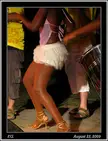 Ebony group dancing Batucada at night, featuring a woman in a pink top and white short skirt