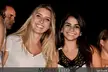 Two smiling beautiful women, one with blonde hair in a white shirt and one with dark hair in a black lace top