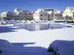Frozen swimming pool and residential buildings in Ifrane, Morocco, covered in snow under a blue sky