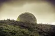 Weather dome on Cape Fugui, a large geodesic dome on a lush green hillside under a cloudy sky