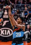 McKinnie in a blue and black Cleveland jersey with number 28 shooting a basketball, showing arm tattoos.