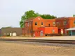 The former Chillicothe Amtrak station featuring a red brick building and grey warehouse by railroad tracks.