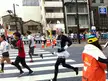 Runners in athletic wear and a person in a white tutu and wig participating in a city marathon