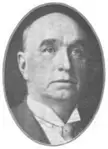 James S. Stack in a black and white vintage photo, wearing a suit and tie.