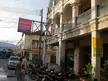 A couple walking past a Mama's Massage sign and parked motorcycles on a city block.