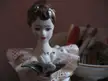 Close-up of a porcelain figurine of a woman with pale skin in a strapless off-the-shoulder dress holding a white flower