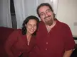Noam and Valerie smiling and posing together indoors in casual red shirts.