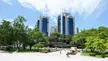 Dëshmorët e Kombit Boulevard in Tirana with blue glass skyscrapers, green trees, and people walking in the plaza