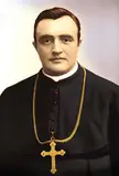 Bishop Georg Heinrich Maria Kirstein in black clerical garment with red piping and a gold cross necklace