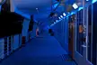 Blue cruise ship deck at night with wooden flooring and blue lights