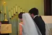 Back view of a couple in a white strapless dress and veil and a black suit in a room with candles