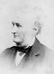 George W. Dumbell in a black and white vintage photo wearing a dark suit and bowtie