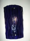 Pretty sconce featuring a vertical, wavy piece of deep blue translucent glass art on a white wall