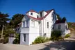 A white shingle-sided house with a red roof in the Arena Cove Historic District.