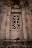 Close-up of a Jali carved stone window in a weathered sandstone wall of ancient architecture.