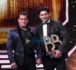 Sidharth Shukla in a black tuxedo and white shirt holding a trophy with another man