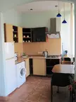 Kitchen interior design with light blue walls, wooden cabinets, a white refrigerator, and a dining table with chairs.
