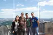 Four people in casual streetwear and blue jeans posing on a New York city skyline observation deck