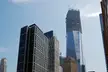 Modern skyscrapers and a construction crane in the WTC city skyline under a clear blue sky.