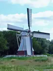 Glimmen landscape photography of a large white windmill in a grassy field with a person in a blue shirt.