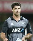 de Grandhomme in a black and grey Canterbury sports jersey holding a cricket bat