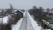Snowy railway tracks receding into the distance past houses and bare trees, minimalist winter landscape photography