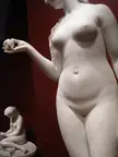 Eve Tempted: close-up of a curvy white marble sculpture of a naked woman holding an apple in a museum