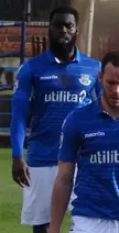 Obileye and a teammate in blue sports jerseys and white shorts on a soccer field.