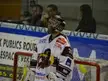 Henri-Corentin Buysse as an ice hockey goalie in athletic wear and a face mask standing before a net.