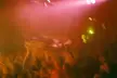 Kanye West concert photo of a crowd lifting a person on their shoulders in a red-lit venue