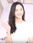 Park Ji-hyun smiling and waving, wearing a white t-shirt with long dark hair