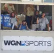 Eddie Vedder and a group of friends in casual clothing and tank tops in a WGN Sports broadcast booth