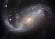 A glowing barred spiral galaxy with swirling arms of stars and dust in outer space.