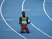 Selemon Barega in a green Ethiopia tank top and red shorts kneeling on a blue running track