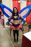 Meg Turney in a blue butterfly costume with purple hair and large wings at a convention booth