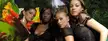 Cuban girls in black tops posing together in a tropical forest with a waterfall and lush foliage.